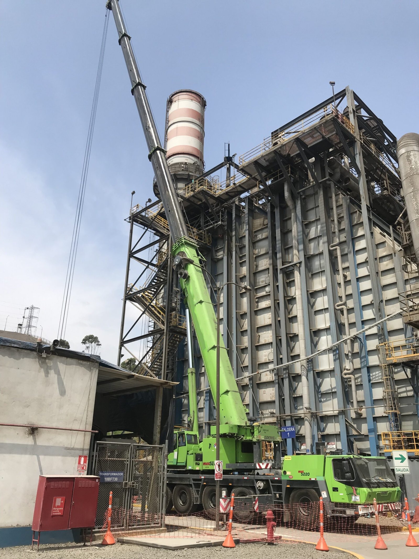 Grúa móvil Liebherr o Tadano verde con pluma extendida, realizando maniobras de izaje en la estructura de una planta de generación eléctrica o industrial.